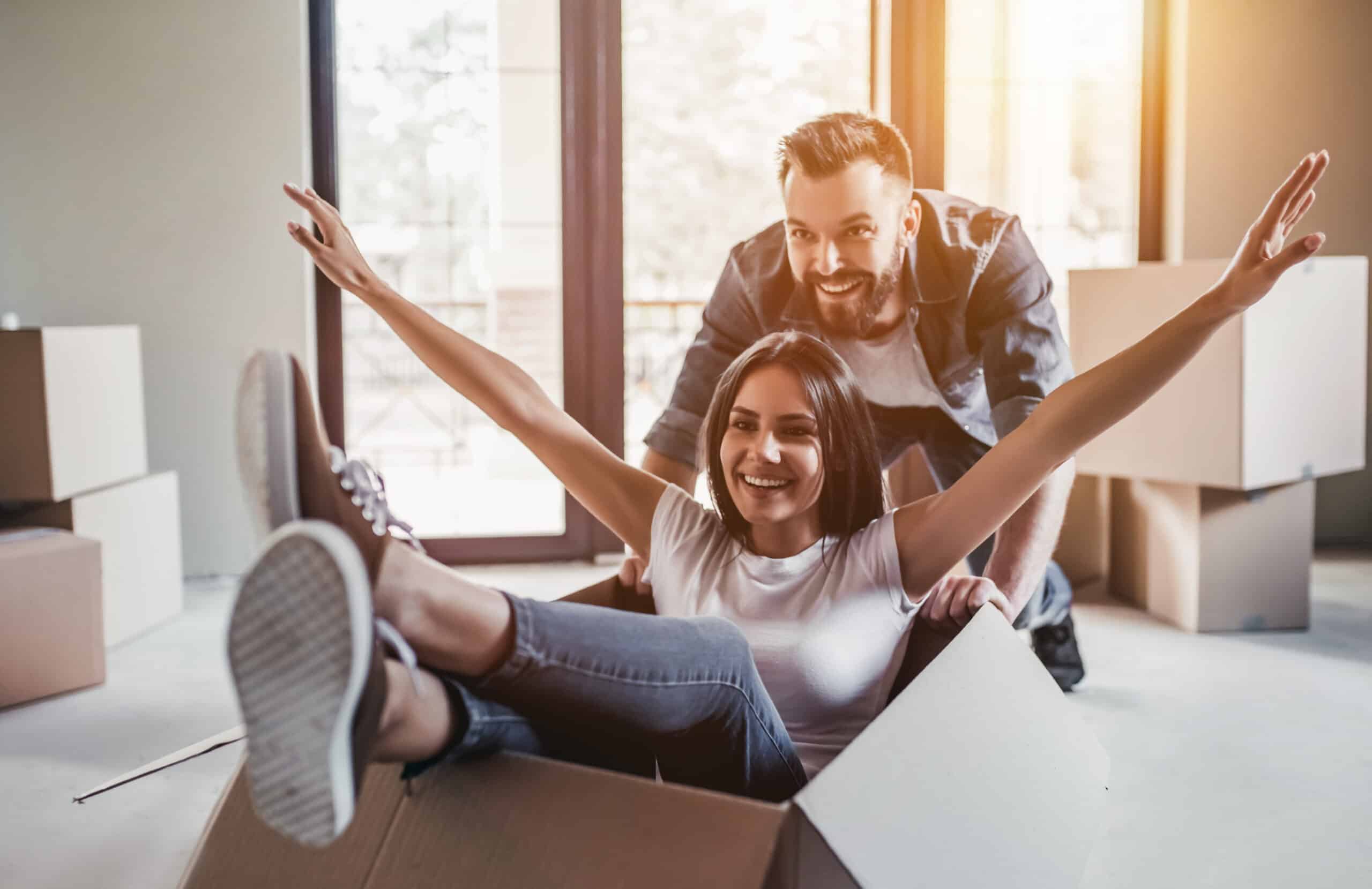 Adult man pushing woman in box, new home they moved into